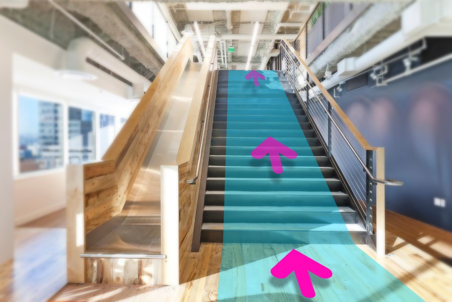 Un escalier sur lequel un chemin bleu et des flèches roses, affichés en réalité augmentée, indiquent la direction à suivre.
